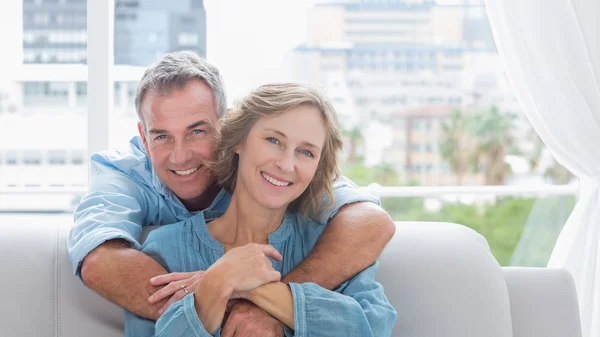 Hombre contento abrazando a su esposa en el sofá — Foto de Stock