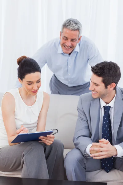 Woman signing a contract as husband and salesman are watching — Stock Photo, Image