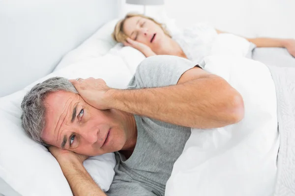 Znudzony człowiek blokowanie jego uszy od hałasu żony chrapanie — Zdjęcie stockowe