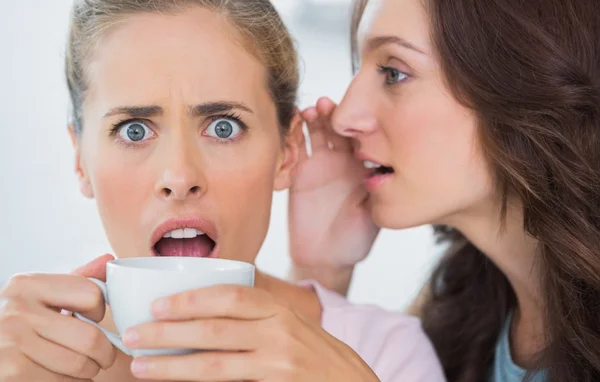 Woman telling secret to her friend and astonishing her — Stock Photo, Image