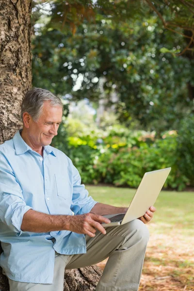 Старик смотрит на свой ноутбук — стоковое фото