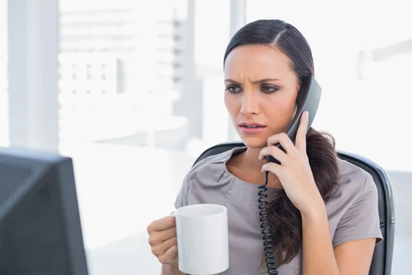 Frowning secretary answering phone — Stock Photo, Image