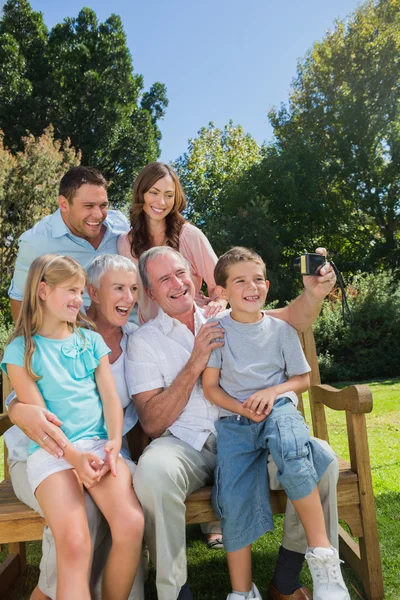 Familia multi generación sentada en un banco tomando fotos de ellos — Foto de Stock