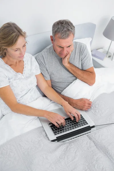 Tankeväckande par tillsammans med sin laptop i sängen — Stockfoto