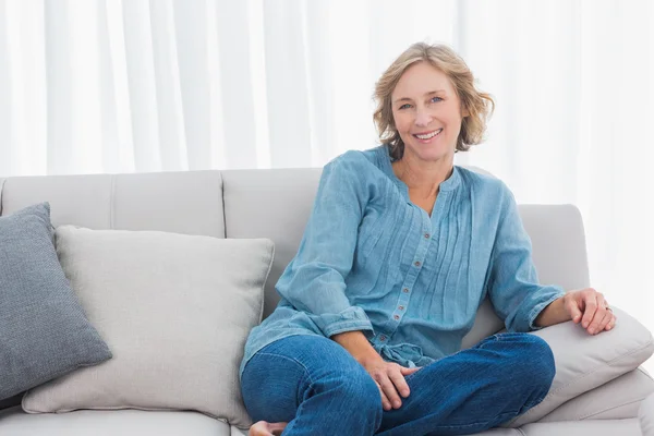 Femme blonde assise sur son canapé — Photo
