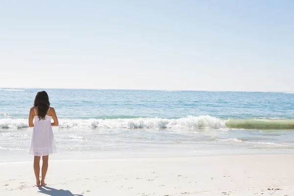 Morena em vestido de sol branco em pé junto à água — Fotografia de Stock