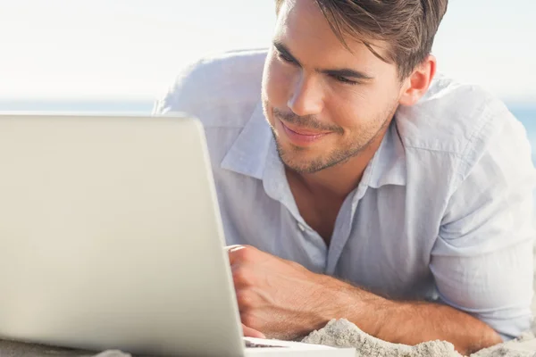 Bonito homem na praia com seu laptop — Fotografia de Stock