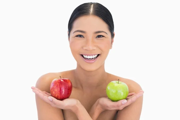 Улыбающаяся натуральная брюнетка держит яблоки в обеих руках — стоковое фото