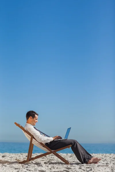 Joven hombre de negocios en su silla de cubierta usando su computadora portátil — Foto de Stock