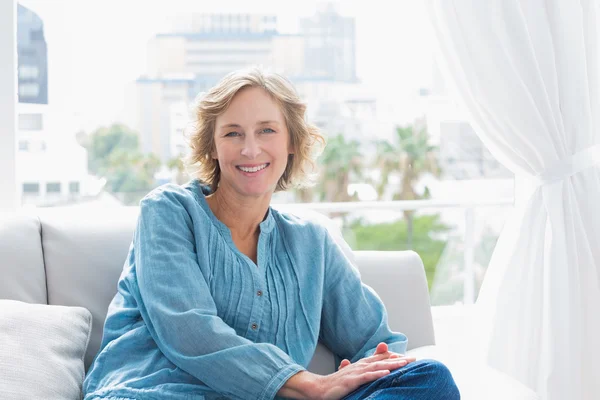 Content blonde woman sitting on her couch — Stock Photo, Image