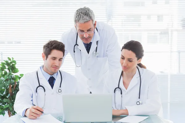 Equipe de médicos concentrados trabalhando em conjunto com seu laptop — Fotografia de Stock