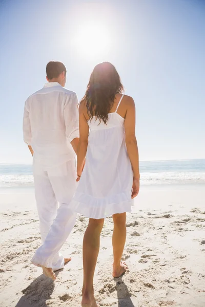 Attractive couple holding hands and walking to the water — Stock Photo, Image