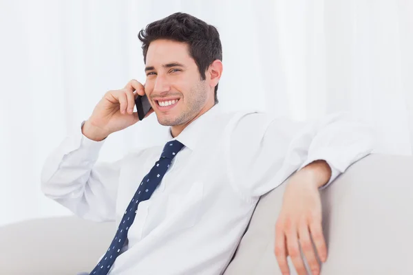 Empresário chamando com seu telefone celular no sofá — Fotografia de Stock