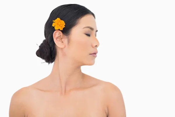 Zamyšlený tmavé vlasy model s oranžová květina ve vlasech — Stock fotografie