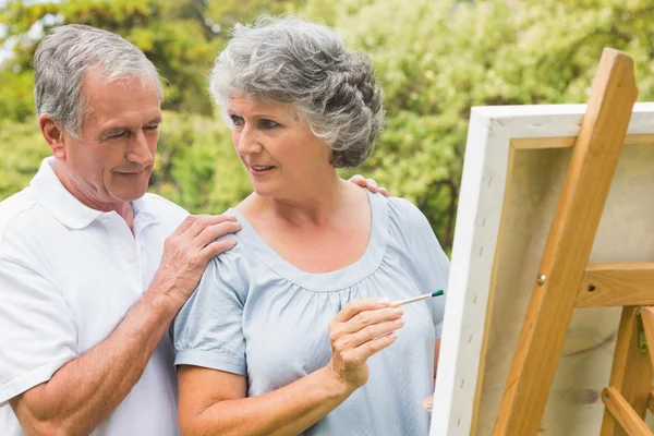 Vrolijke gepensioneerde vrouw schilderij op doek en praten met husba — Stockfoto