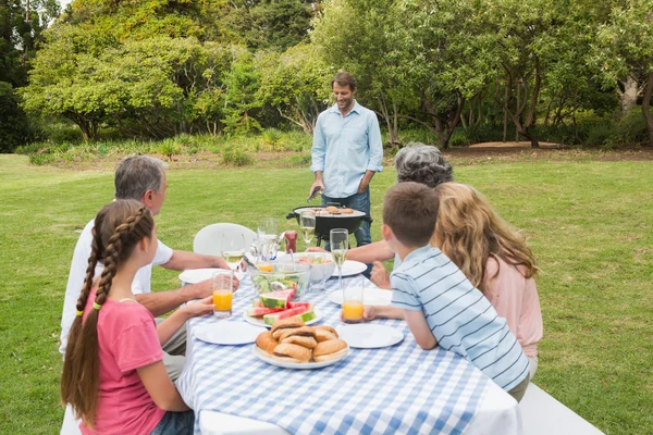 Cheerful extended family watching father at the barbecue — Stock Photo, Image