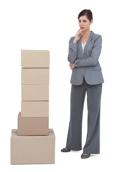 Thoughtful businesswoman posing with cardboard boxes — Stock Photo, Image