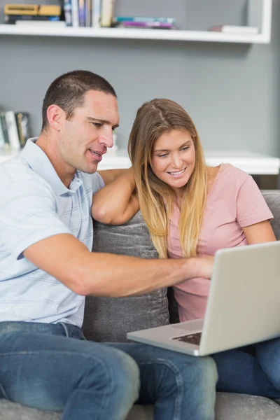 Casal alegre sentado usando laptop no sofá juntos — Fotografia de Stock