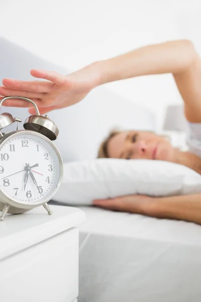 Mujer rubia apagando su alarma en la mañana — Foto de Stock