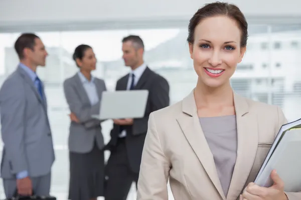 Cheerful businesswoman holding files smiling at camera — Stock Photo, Image