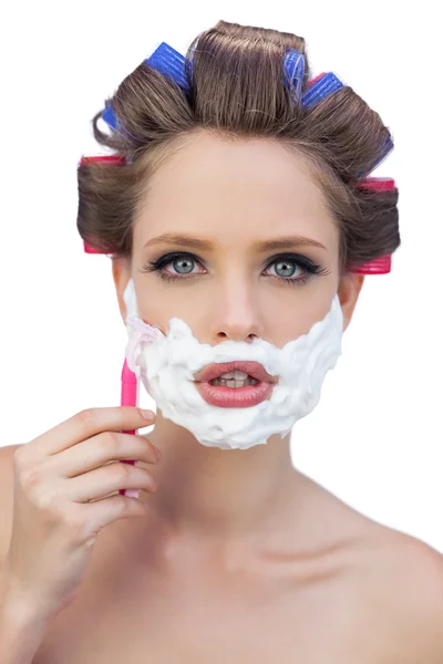 Young model in hair curlers posing with shaving foam and razor — Stock Photo, Image