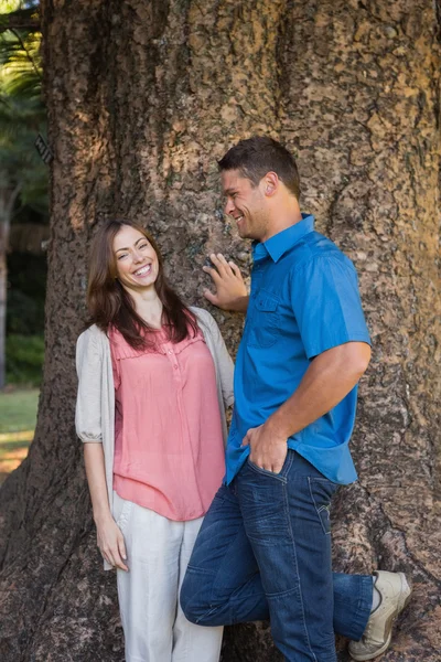 Smiling couple leaning on a tree — Stock Photo, Image