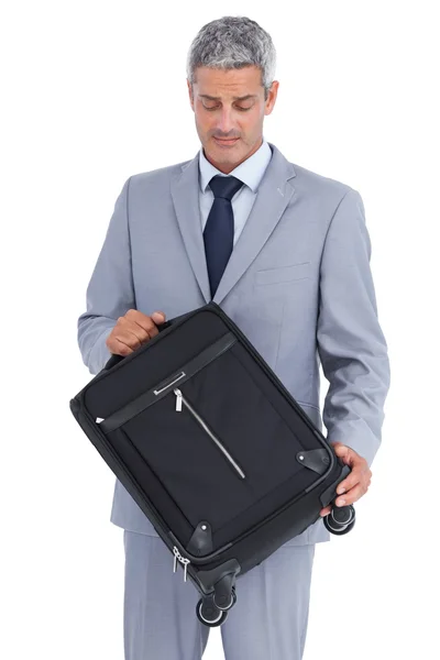 Pohledný podnikatel nošení a při pohledu na jeho kufr — Stock fotografie