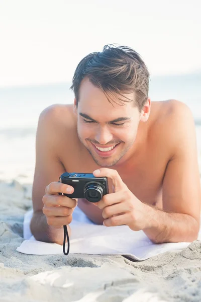 Usměvavý pohledný muž ležící na ručník, při pohledu na svůj fotoaparát — Stock fotografie