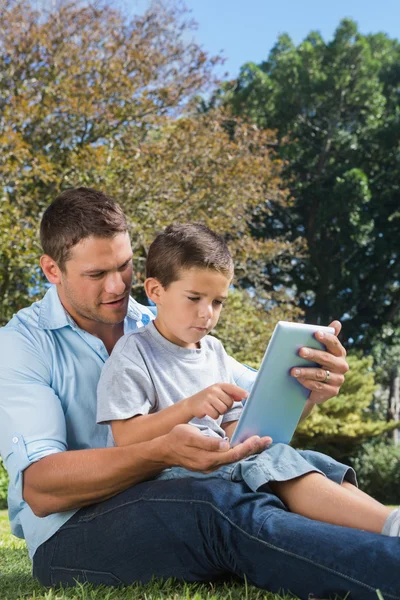 お父さんと息子の公園では、タブレット pc で遊んで — ストック写真
