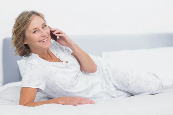 Mulher loira feliz deitada na cama fazendo um telefonema — Fotografia de Stock
