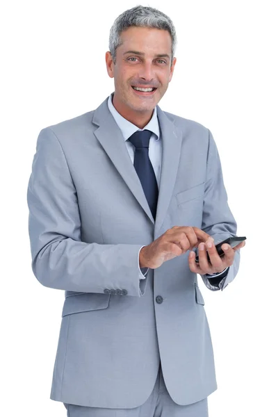 Cheerful businessman sending text message looking at camera — Stock Photo, Image