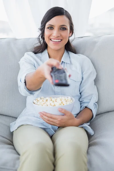 Cheerful pretty brunette watching tv and eating pop corn — Stock Photo, Image