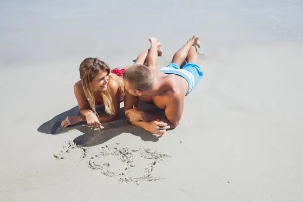 Liebespaar zeichnet in den Sand — Stockfoto