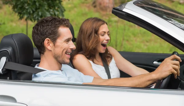 Pareja riéndose conduciendo en un convertible plateado — Foto de Stock