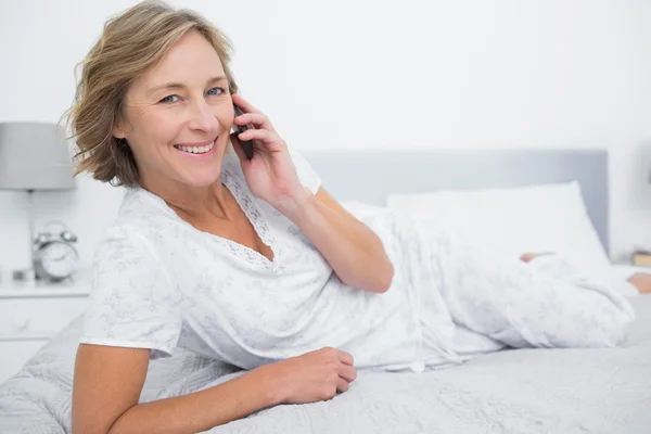 Relajada mujer rubia acostada en la cama haciendo una llamada telefónica —  Fotos de Stock