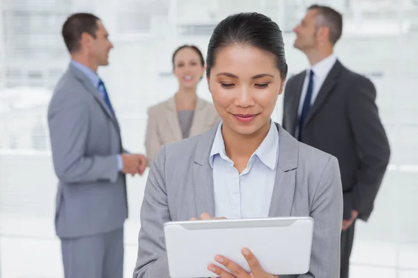 Mujer de negocios con su PC tableta mientras sus colegas hablando togeth —  Fotos de Stock