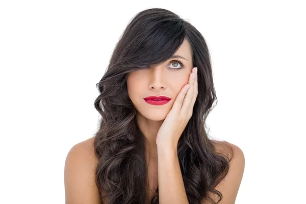 Sensual brunette with red lips touching her cheek looking up — Stock Photo, Image