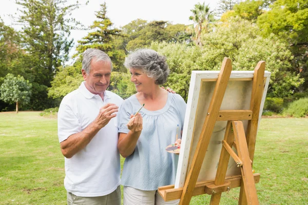 Sorrindo aposentado mulher pintura na lona com o marido — Fotografia de Stock