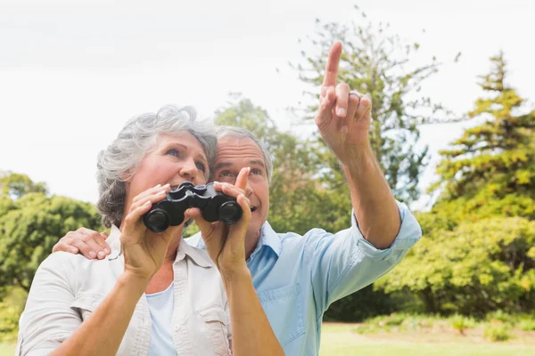 Homem mostrando algo para sua esposa segurando binóculos — Fotografia de Stock