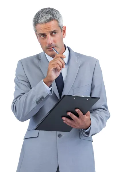 Pensive businessman holding clipboard and taking notes Royalty Free Stock Photos