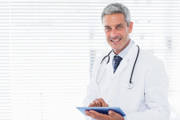Smiling doctor using tablet pc Stock Image