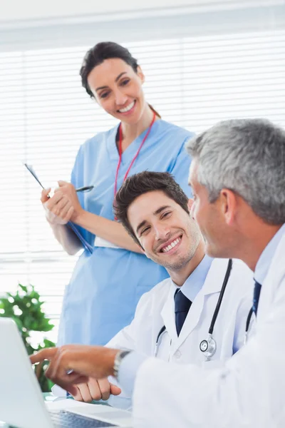 Enfermera feliz escuchando a los médicos hablar de algo en thei — Foto de Stock