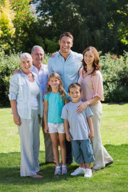 Smiling family and grandparents in the park clipart