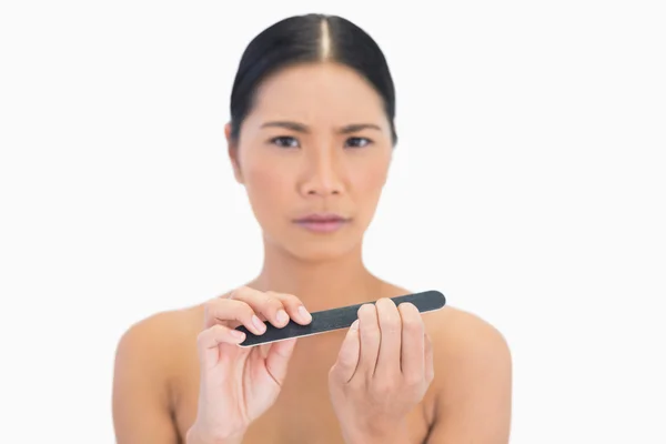 Frowning natural brunette using nail file — Stock Photo, Image