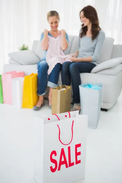 Friends looking at purchase and shopping bag on foreground — Stock Photo, Image