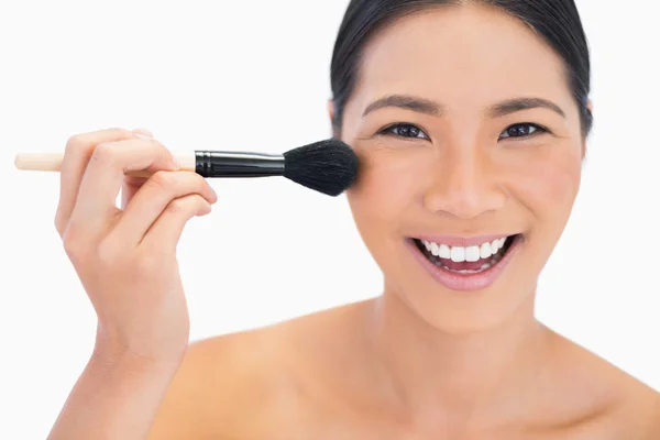 Smiling dark haired model applying powder on her face — Stock Photo, Image