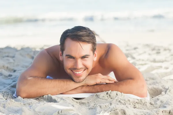 彼のタオルの上に横たわるビーチでハンサムな男の笑みを浮かべてください。 — ストック写真
