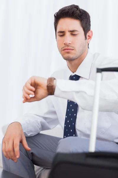 Un hombre de negocios serio con su equipaje esperando un vuelo — Foto de Stock