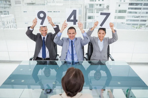 Smiling interview panel holding signs above their head giving ma — Stock Photo, Image