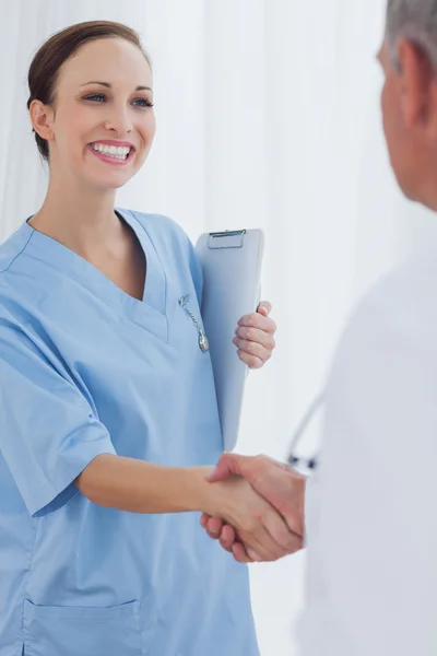 Cheerful pretty surgeon welcoming her new workmate — Stock Photo, Image